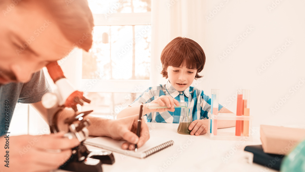 Youn Bearded Father Teaching Son in Shirt at Home. Youn Bearded Father Teaching Son in Shirt at Home.