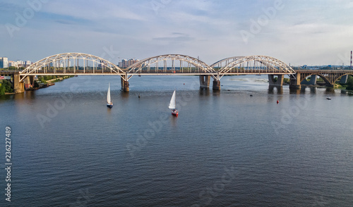 Aerial top view of Darnitsky bridge, yachts and boats sailing in Dnieper river from above, Kiev (Kyiv) city skyline, Ukraine 