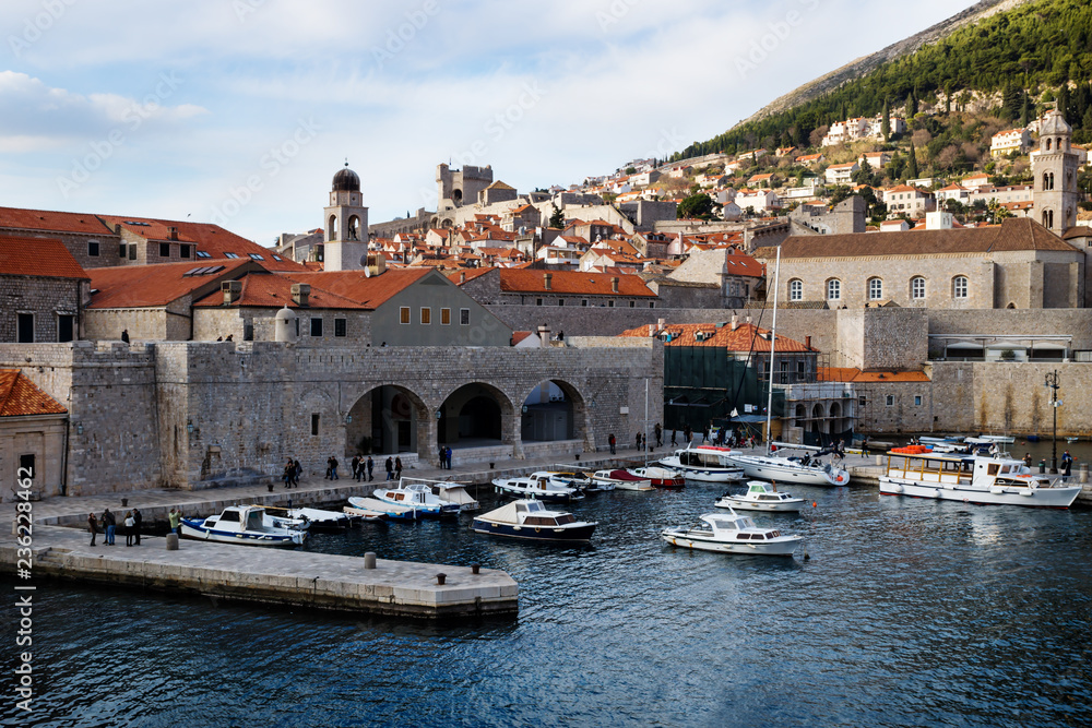 Harbor of Dubrovnik with boats and view on pier and mountain in the background in winter, Croatia