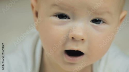 Close-up of a happy  five-month-old baby looking at the camera and smiling in slow motion.
