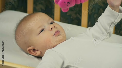 Mother play with her newborn baby lying on crib in slow motion.