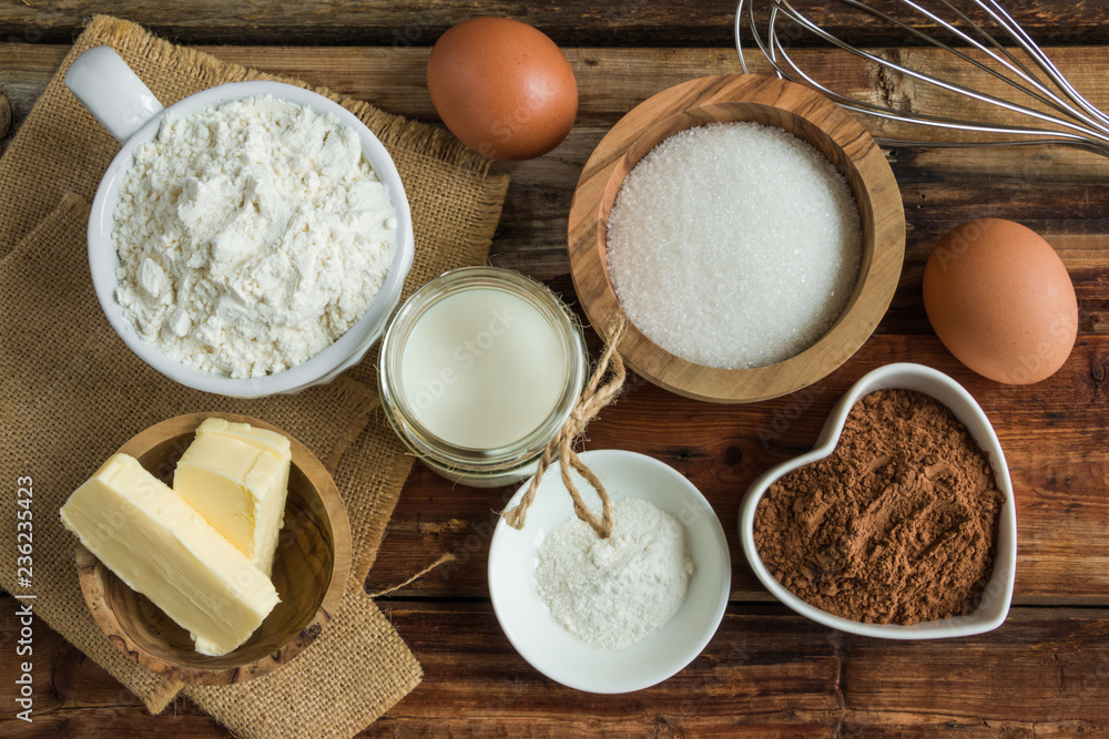 Ingredients for chocolate dough - flour, cocoa, sugar, eggs, butter, milk, baking powder on the wooden rustic table, top view. Ingredients for chocolate dough - flour, cocoa, sugar, eggs, butter, milk, baking powder on the wooden rustic table, top view.