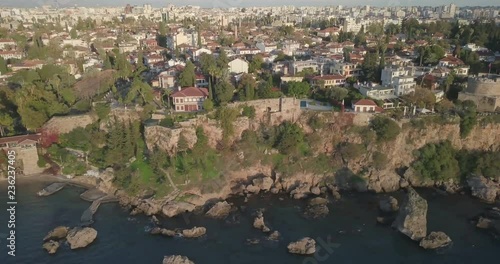 Aerial drone video above water tracking right of rocky cliffs below Kaleici old town to Hidirlik Castle and Karaalioglu Park late afternoon in Antalya, Turkey. 4k at 23.97fps photo