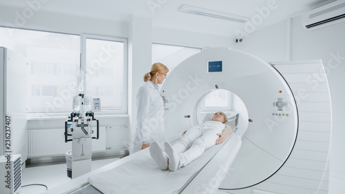 In Medical Laboratory Female Radiologist Controls MRI or CT Scan with Female Patient Undergoing Procedure. High-Tech Modern Medical Equipment.  photo