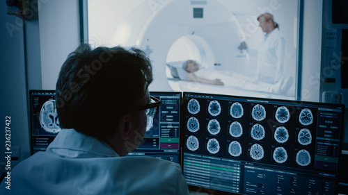 In Medical Laboratory Patient Undergoes MRI or CT Scan Process under Supervision of Radiologist, in Control Room Doctor Watches Procedure and Monitors Brain Activity.