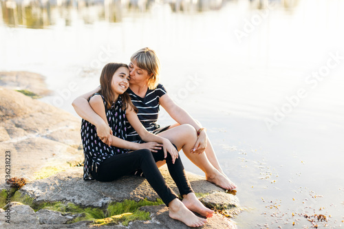 Mother and daughter sitting by the sea at sunset in Blekinge, Sweden photo