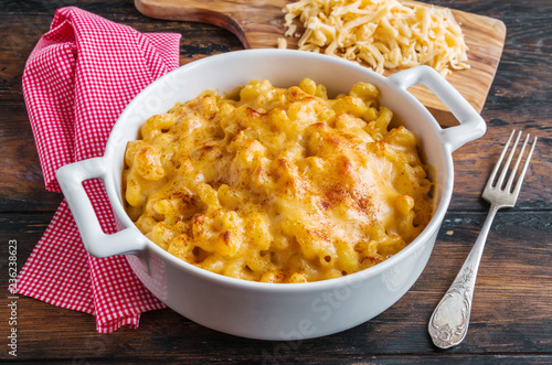 American dish Mac and Cheese pasta in white casserole on wooden rustic table.