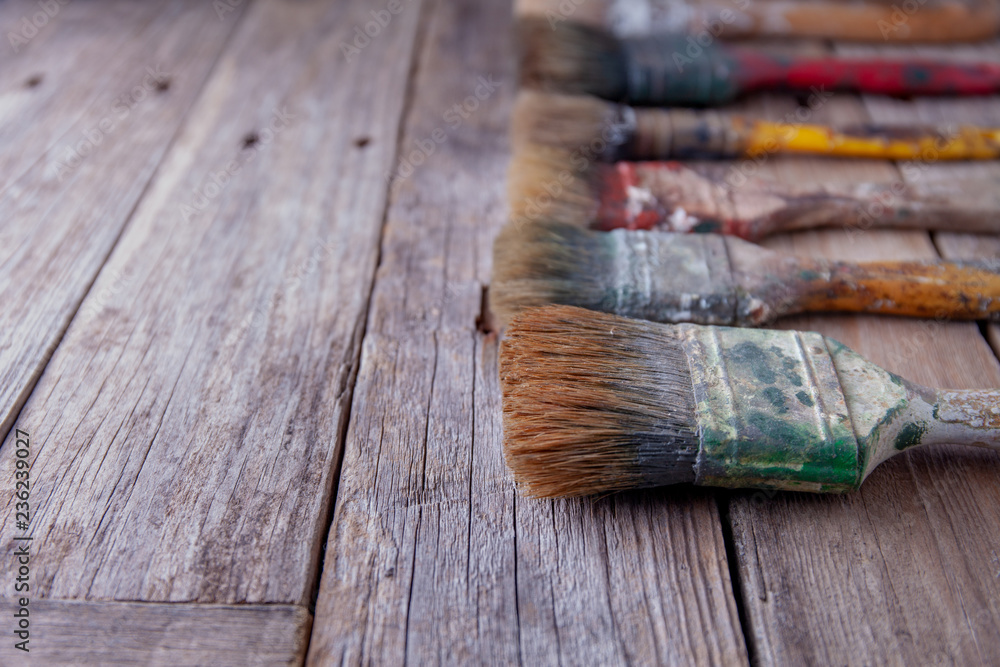 Old paintbrushes stained with paint on rustic table Old paintbrushes stained with paint on rustic table