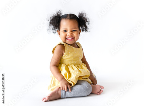 Foto Happy little girl in a yellow dress sitting
