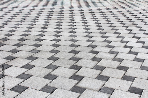 Light and dark stone tiles driveway made as optical depth illusion texture on warm sunny spring day