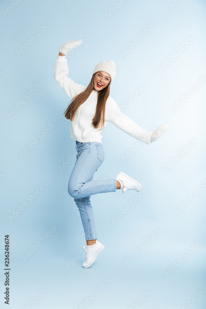 Young woman wearing winter hat posing isolated over blue wall background. Young woman wearing winter hat posing isolated over blue wall background.