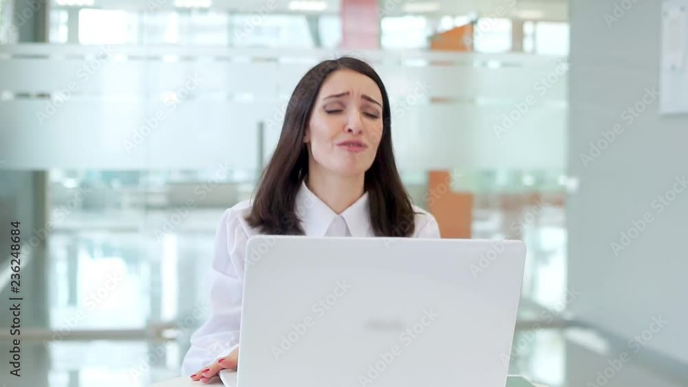 The girl at work at the table is emotional, worried because the laptop broke. The girl at work at the table is emotional, worried because the laptop broke.