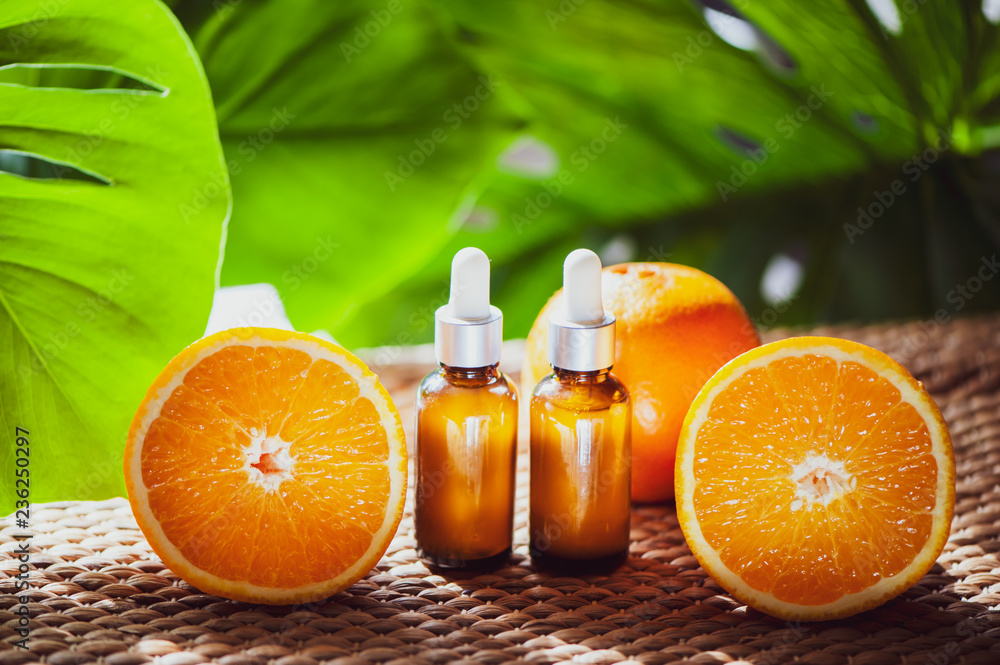 Bottles with orange oil, fresh fruit whole and half on a natural tropical background. Bottles with orange oil, fresh fruit whole and half on a natural tropical background.