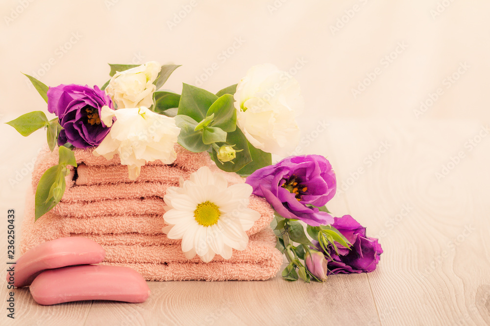 Stack of soft terry towels with flowers on wooden boards Stack of soft terry towels with flowers on wooden boards