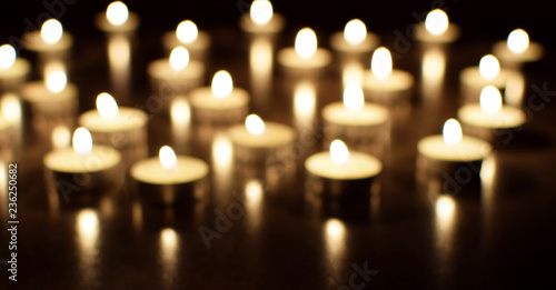 Tea light candles burning in darkness. Advent or memorial prayer candle flame.