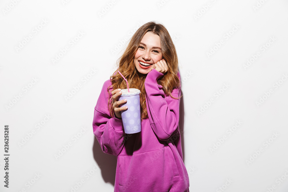 Portrait of adorable woman 20s wearing sweatshirt drinking soda from paper cup using straw, isolated over white background Portrait of adorable woman 20s wearing sweatshirt drinking soda from paper cup using straw, isolated over white background