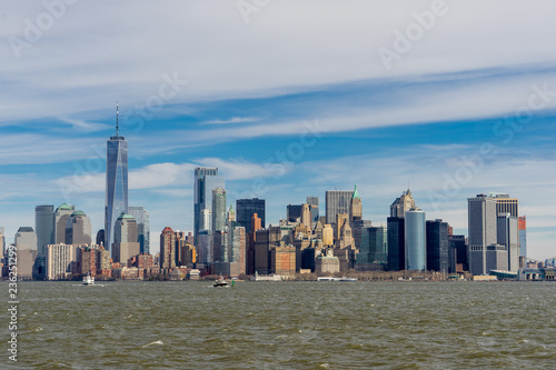 View of Manhattan downtown from ferry at daytime with cloud blue sky background. New York skyscrapers at Lower Manhattan  New York City  USA.