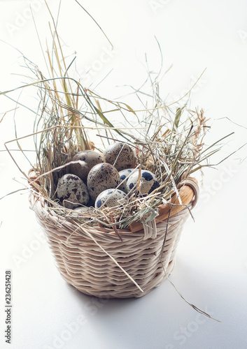 Quail eggs on straw in basket