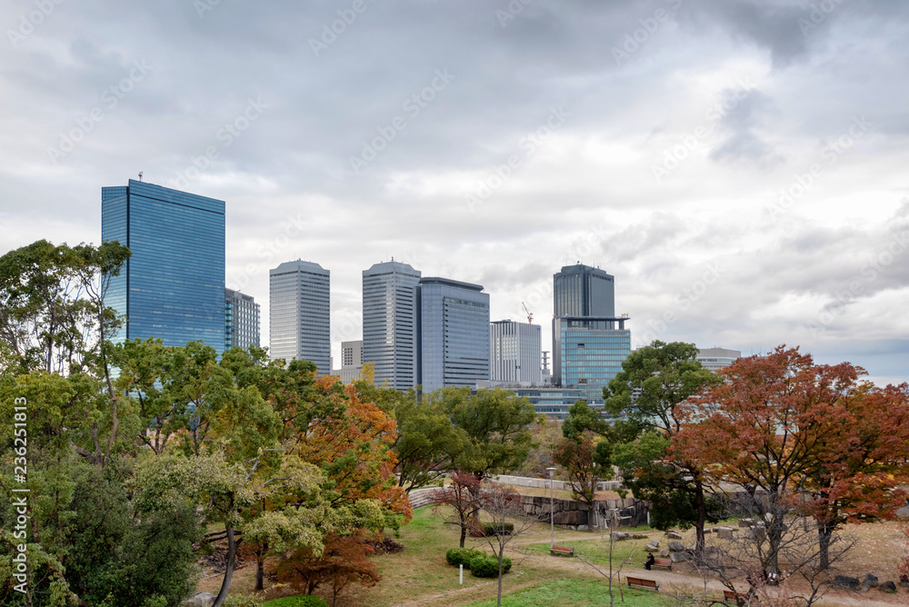Scene at the Osaka Castle grounds on a cloudy day in Osaka, Japan with modern buildings in the background