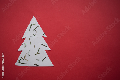 White paper Christmas tree, Festive confetti, christmas decoration on the red background with copy space