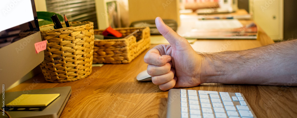 close-up of a man typing on the keyboard of computer in the evening in the home office with ok sign 