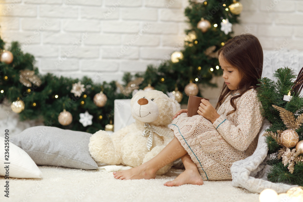 Cute girl drinks hot cocoa and plays with teddy bear at home. Christmas Cute girl drinks hot cocoa and plays with teddy bear at home. Christmas