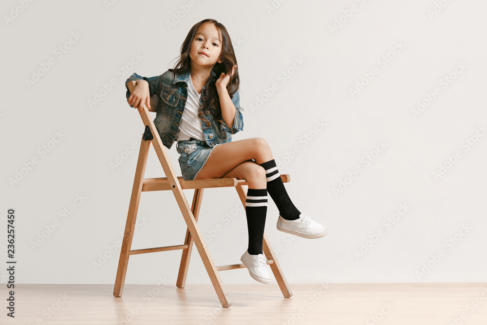 © master1305 - Full length portrait of cute little kid girl in stylish jeans clothes looking at camera and smiling against white studio wall. Kids fashion concept © master1305 - Full length portrait of cute little kid girl in stylish jeans clothes looking at camera and smiling against white studio wall. Kids fashion concept