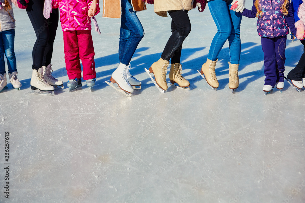 Close-up of the skates from the skaters on the ice surface. Skate on the ice in the company of friends. Skate rental. Place for text.