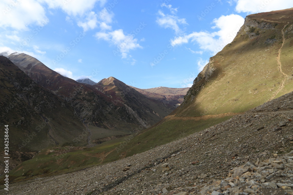 Fototapeta premium Track passing through the edge of the mountain under shiny sky