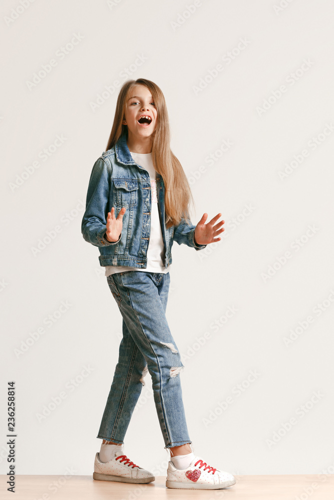 Full length portrait of cute little teen girl in stylish jeans clothes  looking at camera and smiling against white studio wall. Kids fashion  concept Stock Photo | Adobe Stock