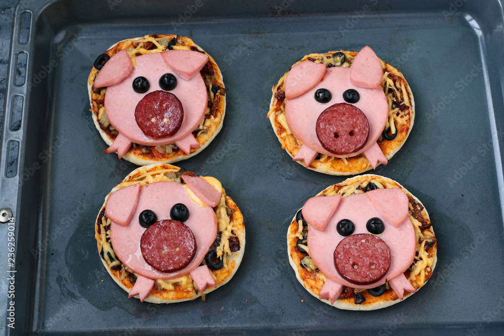 Mini pizza with sausage and cheese in the shape of a cute pig - a symbol of 2019. Idea for children. View from above.