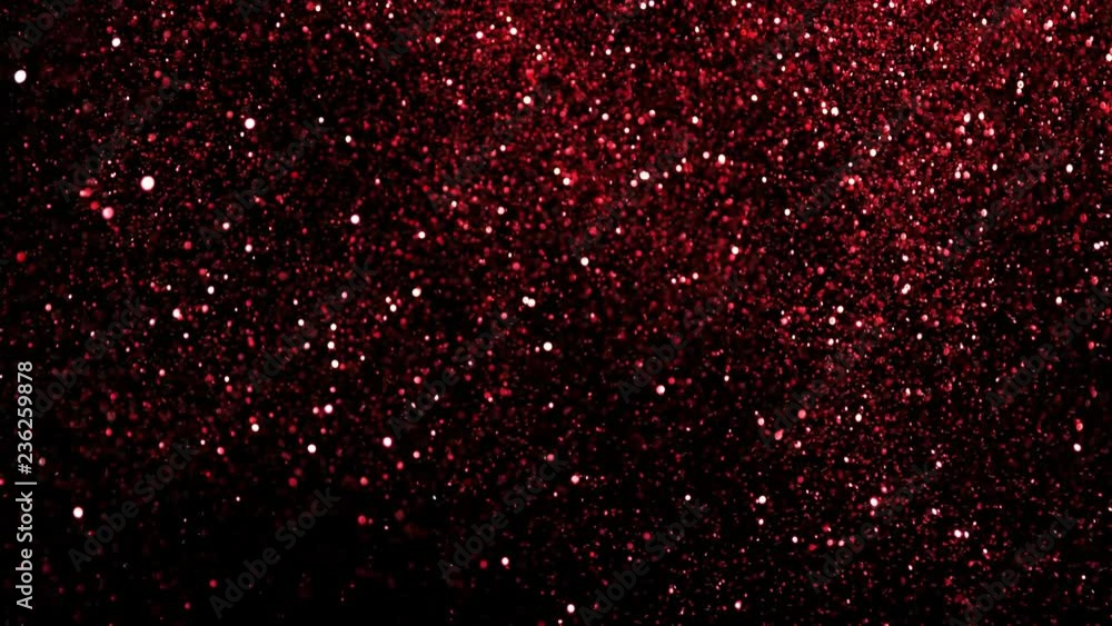 Super slow motion of glittering red particles on black background. Shallow depth of focus. Filmed on high speed cinema camera, 1000 fps. Super slow motion of glittering red particles on black background. Shallow depth of focus. Filmed on high speed cinema camera, 1000 fps.