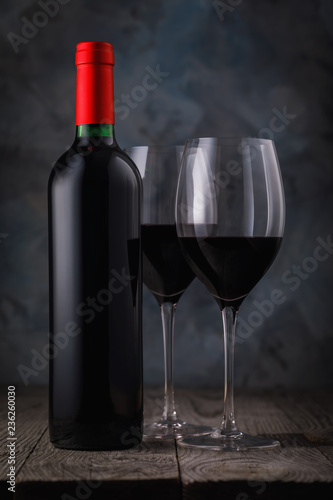 Bottle of red wine and two full glasses on a wooden table closeup