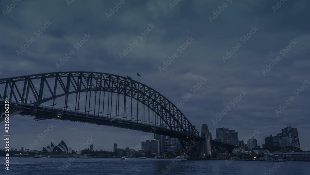 Day to night timelapse of Sydney Harbour Bridge with the cityscape of Sydney skyscrapers and office buildings during nightfall. Day to night timelapse of Sydney Harbour Bridge with the cityscape of Sydney skyscrapers and office buildings during nightfall.