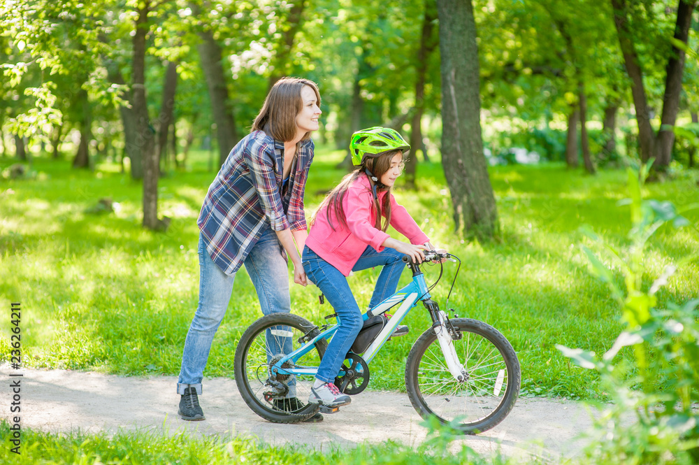 Happy family. Smiling mom teaches her daughter to ride a bicycle in the park Happy family. Smiling mom teaches her daughter to ride a bicycle in the park