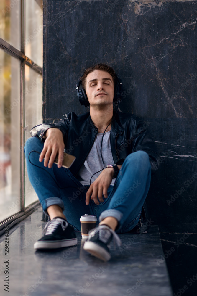Young man listening music on headphones with his eyes closed.
