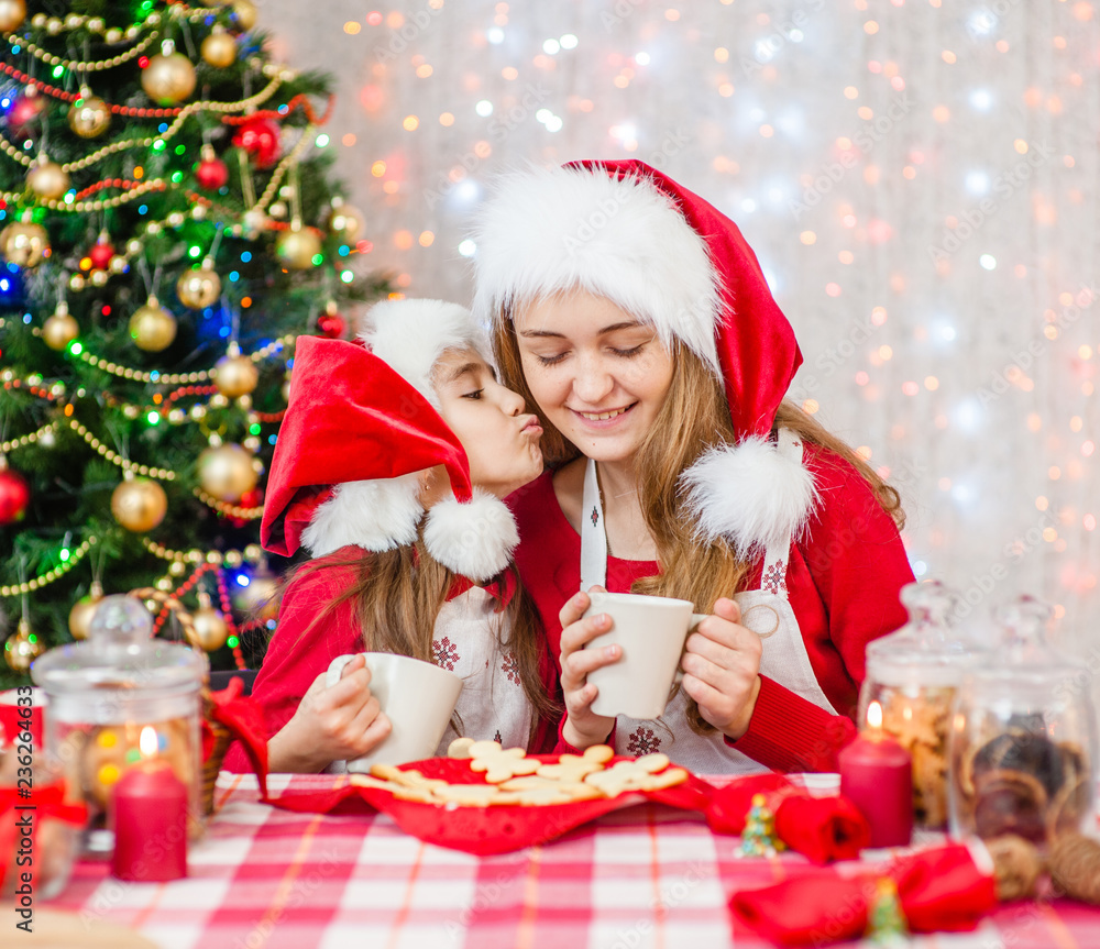 Merry Christmas and Happy Holidays. Girl kisses mom at the christmas table Merry Christmas and Happy Holidays. Girl kisses mom at the christmas table