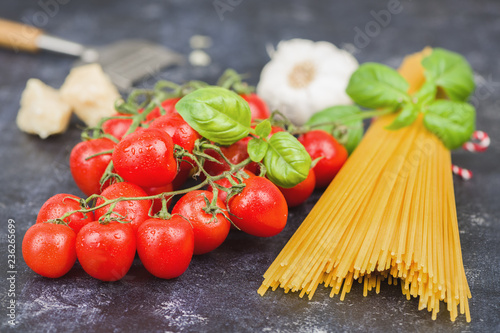 Cherry tomatoes with spaghetti and garnish on dark background. Copy space horizontal.