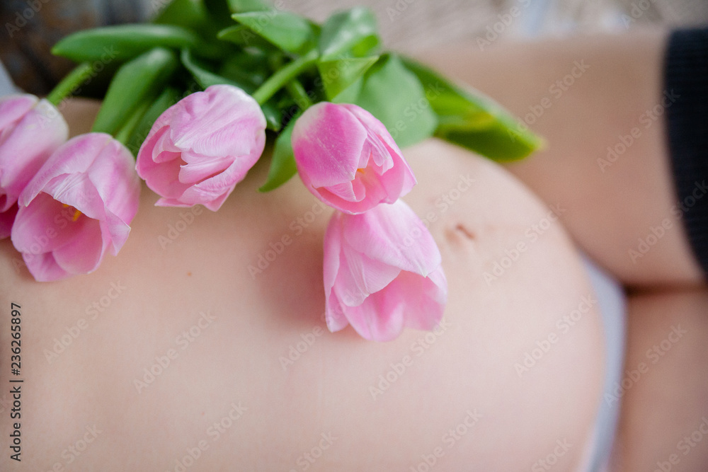 a bouquet of tulips lies on the belly of a pregnant woman a bouquet of tulips lies on the belly of a pregnant woman