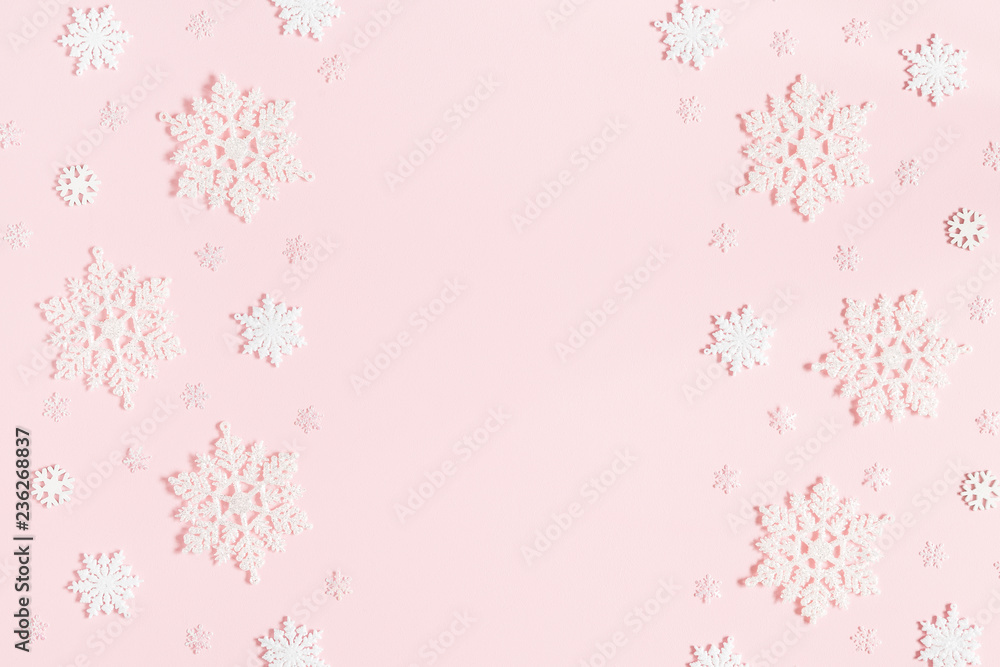 Christmas or winter composition. Frame made of snowflakes on pastel pink background. Christmas, winter, new year concept. Flat lay, top view, copy space