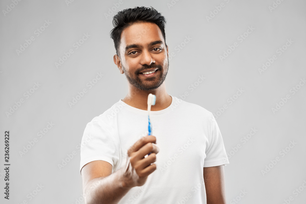 oral care, dental hygiene and people concept - smiling young indian man with toothbrush over gray background oral care, dental hygiene and people concept - smiling young indian man with toothbrush over gray background