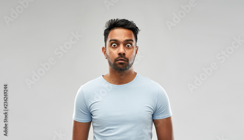 emotion, expression and people concept - shocked or scared man in t-shirt over grey background photo