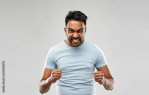 emotion, anger and people concept - angry indian man screaming over grey background
