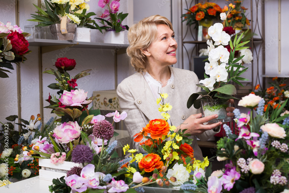 Mature glad female customer choosing flowers