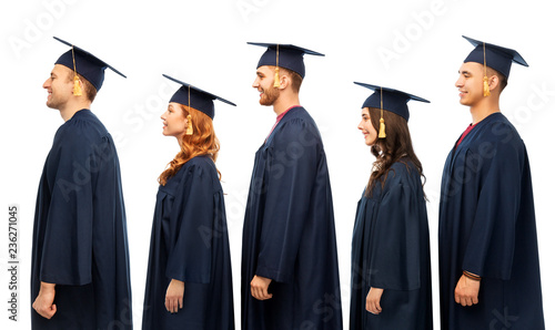 education, graduation and people concept - group of happy graduate students in mortar boards and bachelor gowns over white background