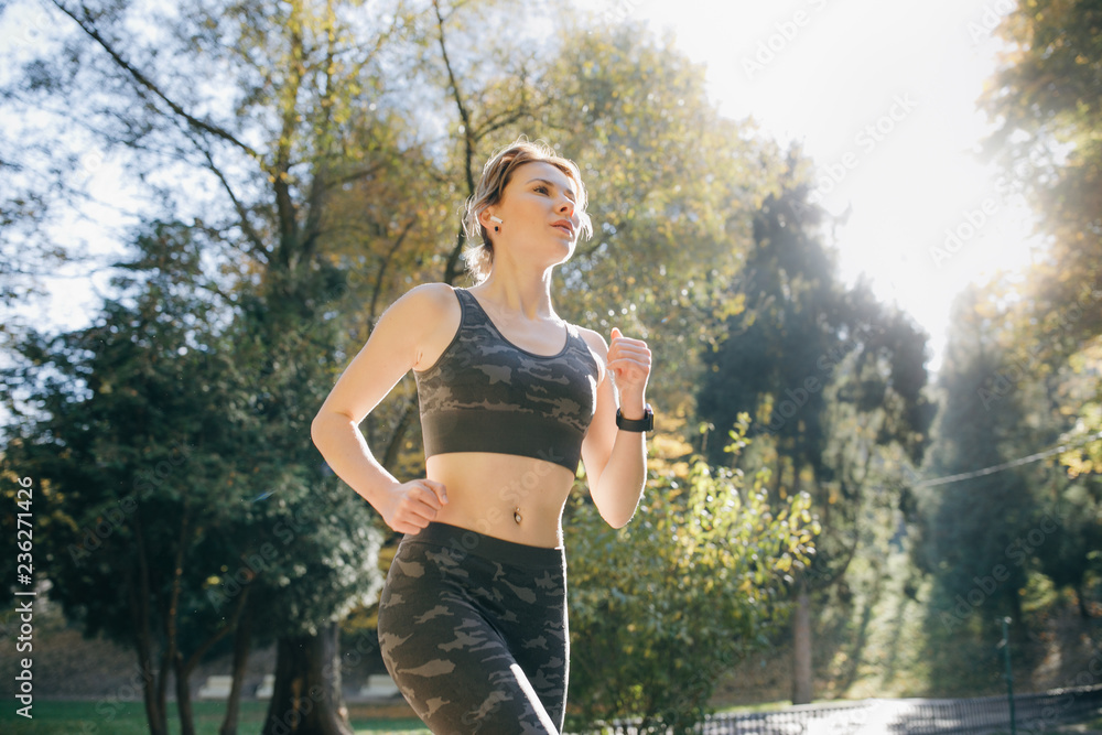 Portrait of attractive brunette female runner running in city park airpods  bluetooth headphones earphones. Healthy fitness athletic woman jogging  outdoors foto de Stock | Adobe Stock