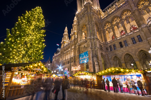 Famous Vienna Christkindlmarkt christmas market in front of town hall with huge Christmas tree at Rathausplatz with tourists and people in festive mood in Advent.