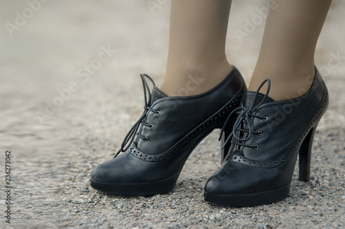 Fashion concept of women's feet in black shoes with high heels.
