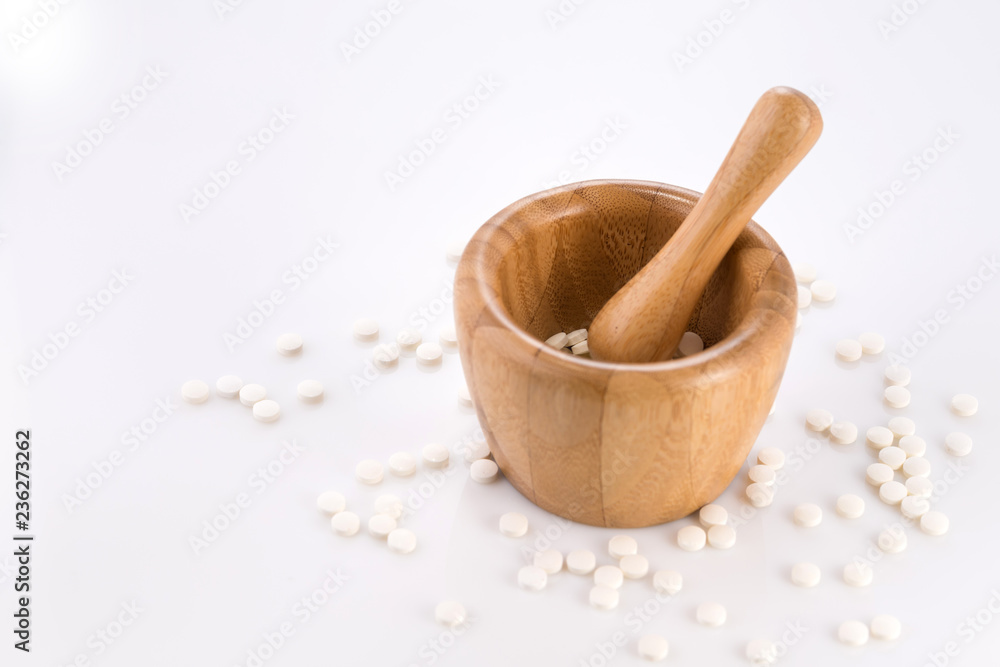 Close-up of small white tablets in a wooden mortar to be ground into powder. Preparation of medicinal mixtures. Close-up of small white tablets in a wooden mortar to be ground into powder. Preparation of medicinal mixtures.