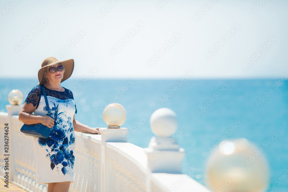 An elderly woman posing, sea at the background